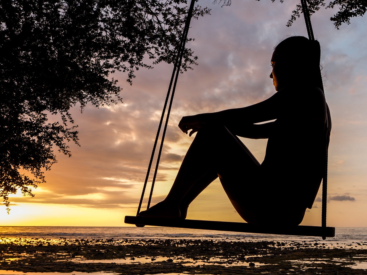Silhouette of Woman thinking on Swing during Golden Hour