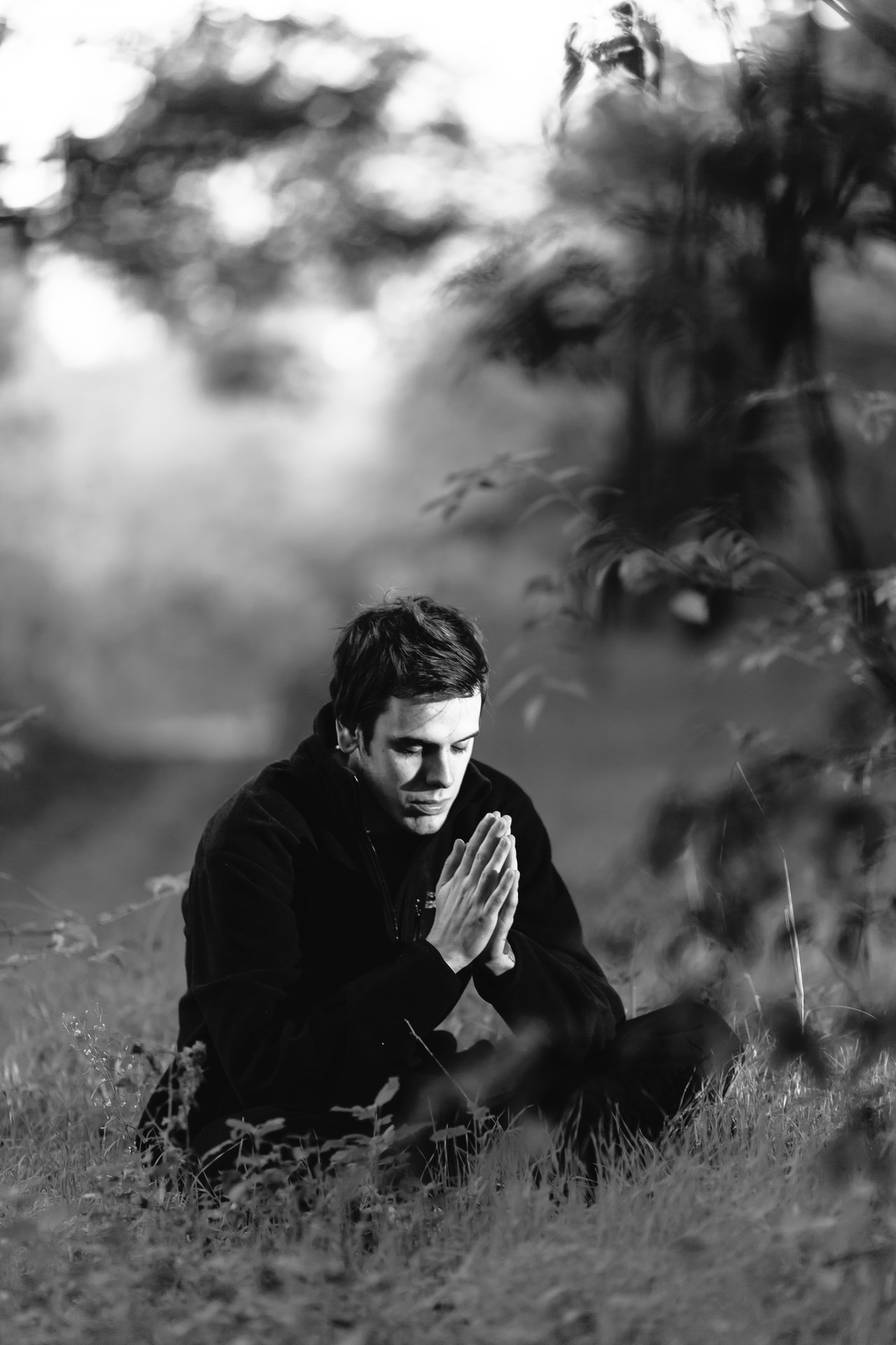 Man sitting on a grass field praying