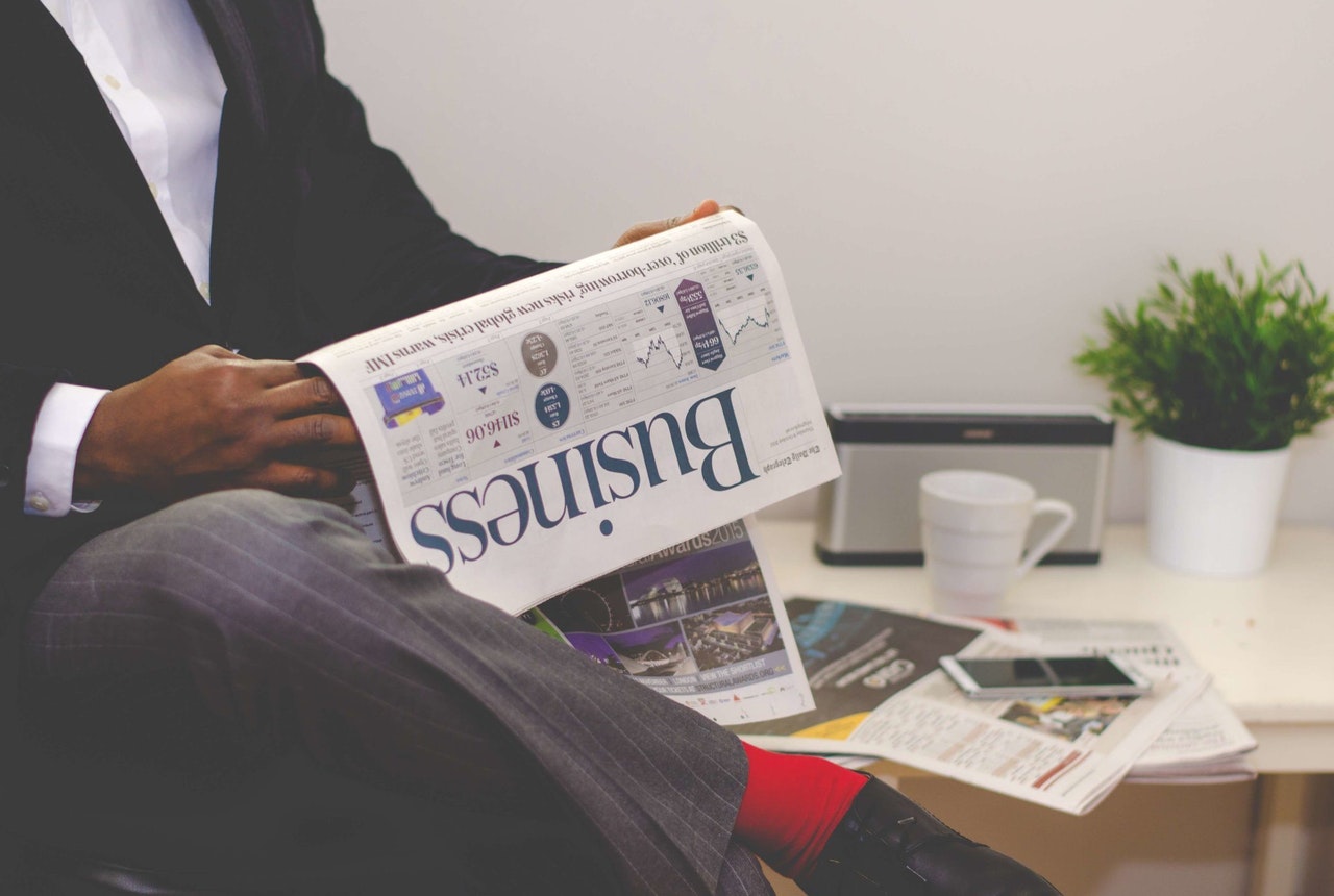 man reading newspaper while sitting near table