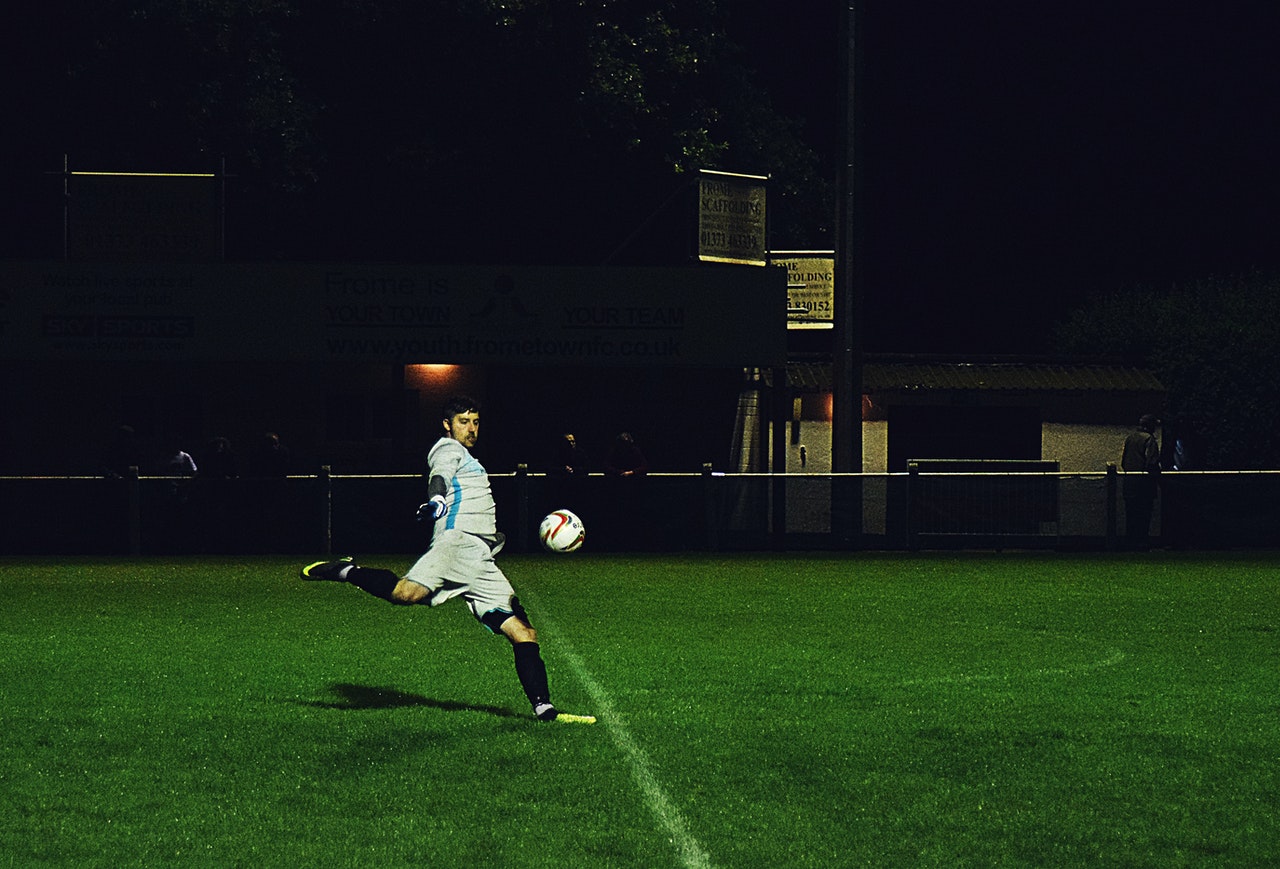 person kicks a soccer ball in field
