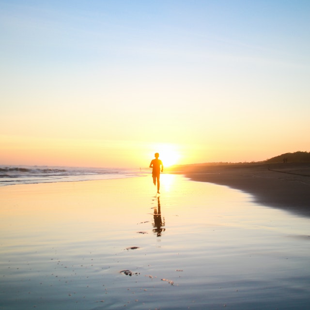 boy running in body of water during sunset 