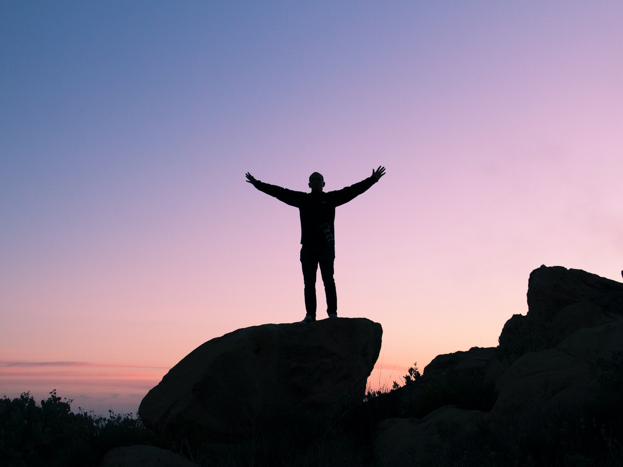 A man in silhouette with his arms spread cheering the good news of the gospel 